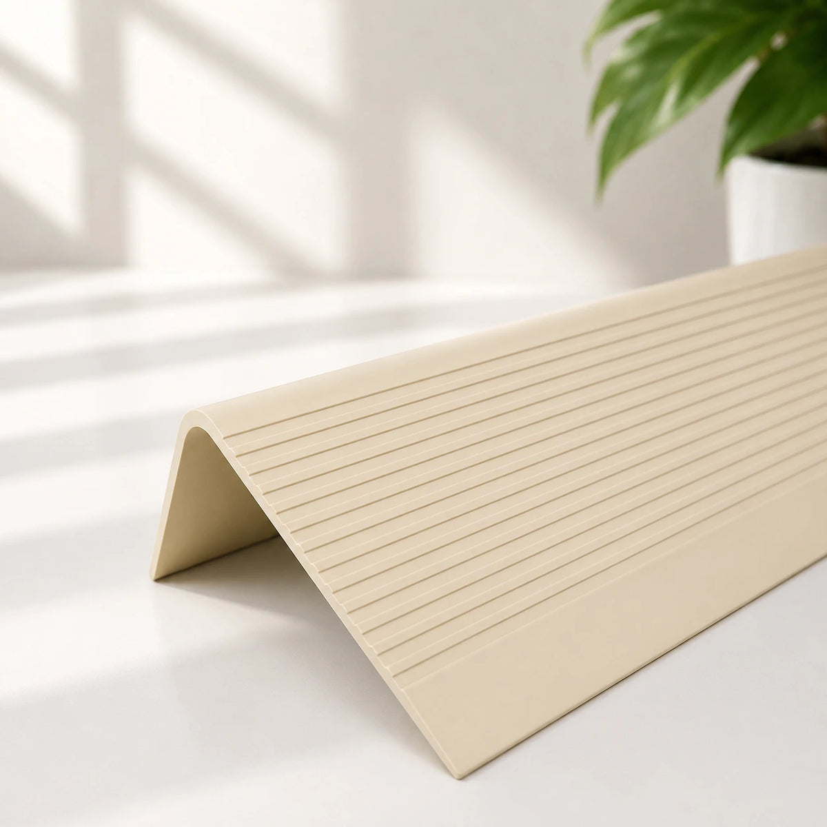 Flexible PVC anti-slip stair nosing profile in beige colour with textured grooved surface for enhanced stair edge safety and protection.