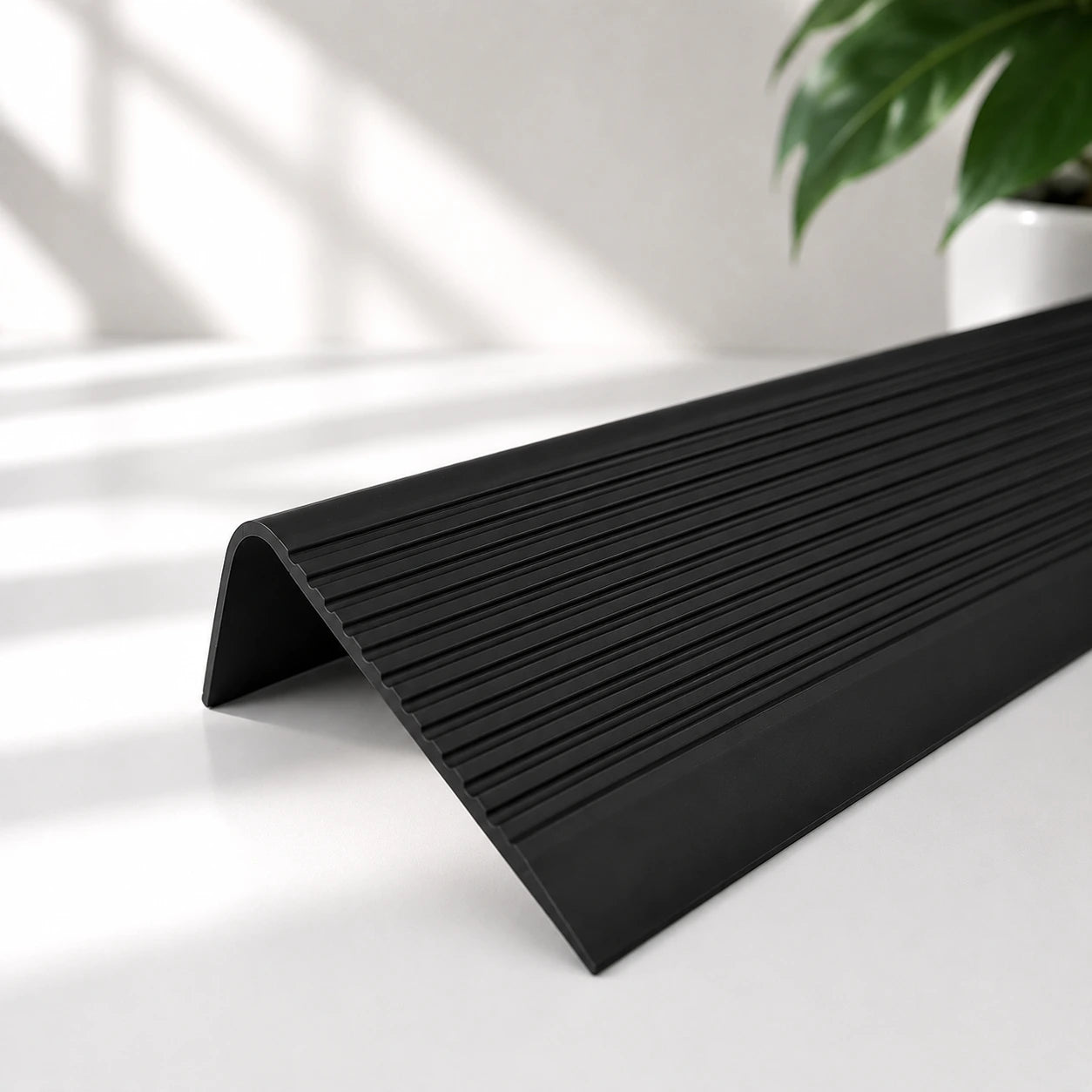 Flexible PVC anti-slip stair nosing profile in black colour with textured grooved surface for enhanced stair edge safety and protection