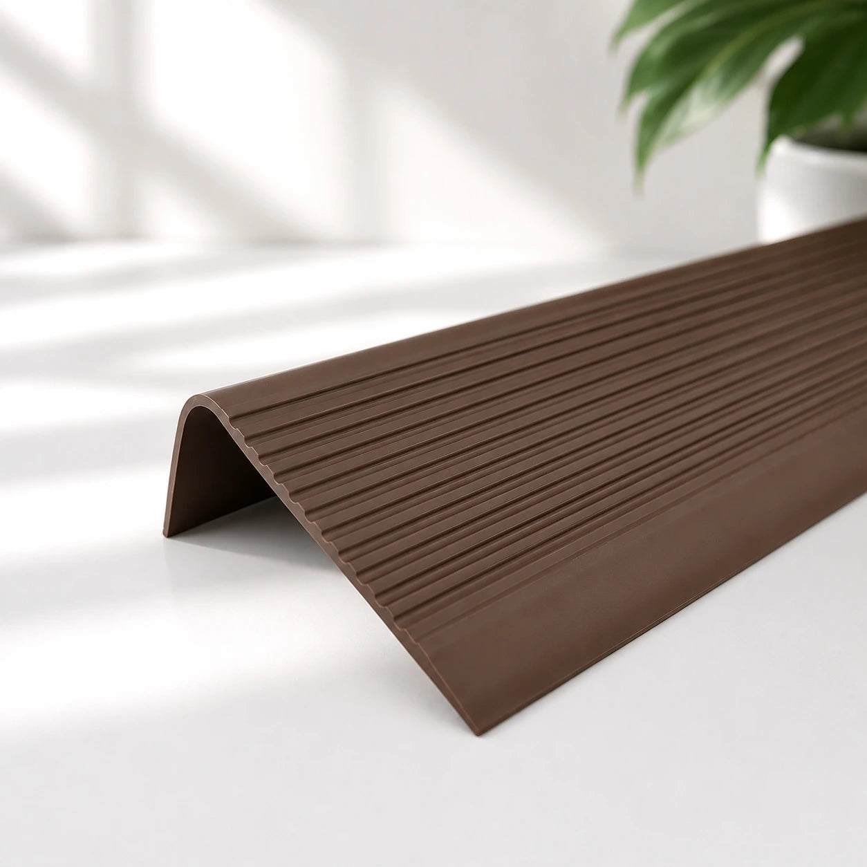 Flexible PVC anti-slip stair nosing profile in brown colour with textured grooved surface for enhanced stair edge safety and protection