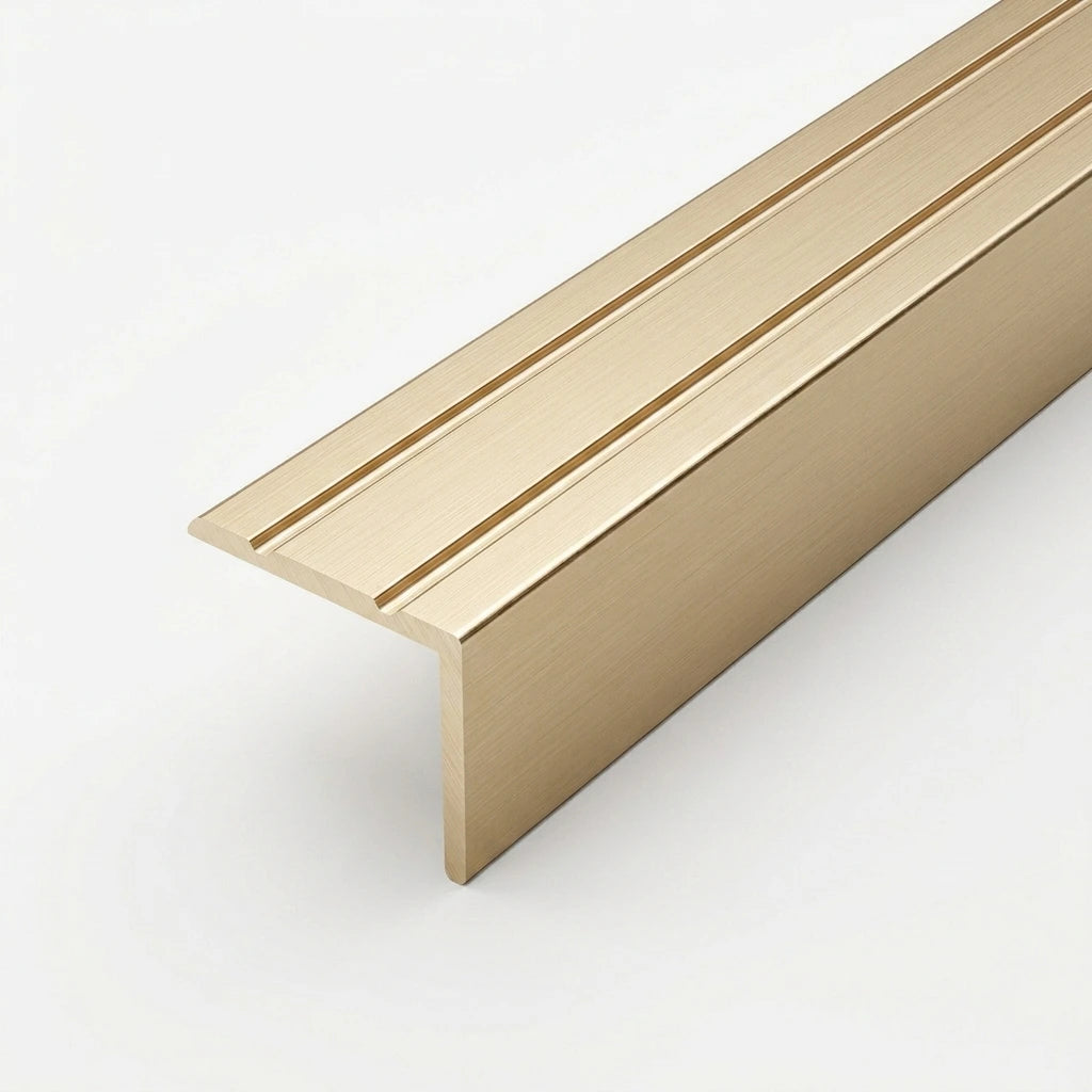 Gold brushed aluminum stair nosing profile with anti-slip grooves, shown in close-up on a white background.